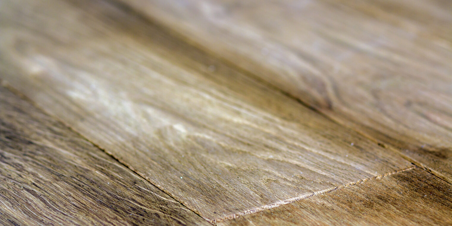 Close-up of weathered wooden planks showing grain and seams in warm brown tones.